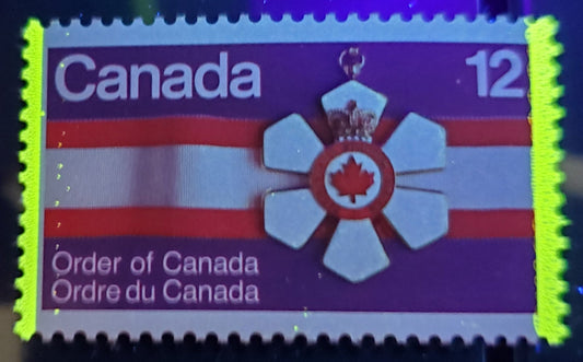 Lot 456 Canada #736var 12c Multicolored Order Of Canada Medal, 1977 Order Of Canada Issue, A VFNH Single On DF2/DF2 Paper With Dotted Extra Tagging Streak Through 'C' Of Canada